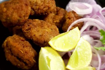 Mutton Tikki next to wedges of lime and slices of onion