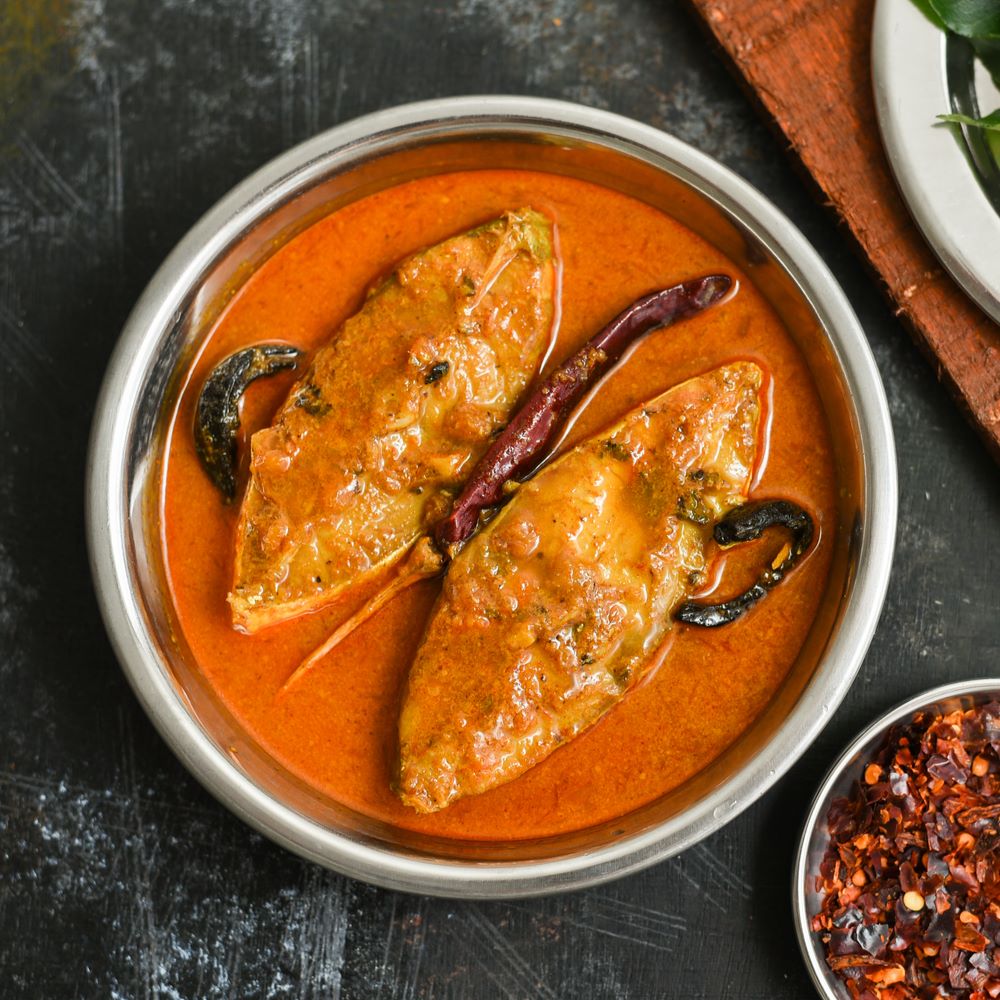 Pomfret Fish Curry in a silver bowl with curry leaves and red chillies.