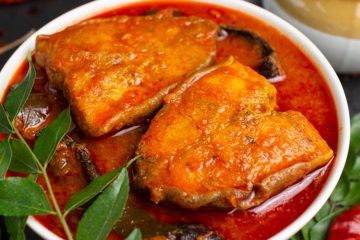 Basa Fish Curry in a white bowl with curry leaves and red chillies.