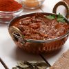 Kashmiri Mutton garnished with coriander leaves along with spices on the side.