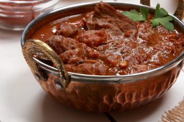 Kashmiri Mutton garnished with coriander leaves along with spices on the side.