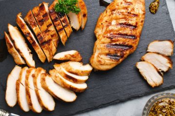 Sliced Honey Mustard Chicken on a black plate garnished with coriander.