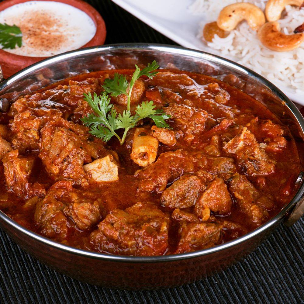 Mutton Tikka Masala served in a brass bowl garnished with coriander leaves.