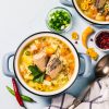 Fish soup in a blue ceramic bowl surrounded by vegetables