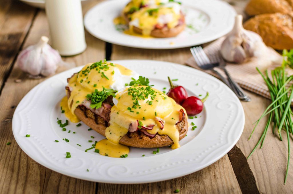 A plate of eggs Benedict with a bread on the side.