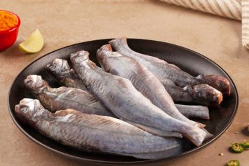 Cut & cleaned Tengra fish in a black bowl on a wooden table.
