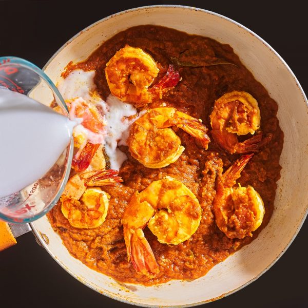 Coconut milk being added to chingri malai curry