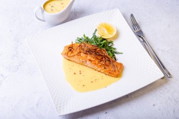 Fish is lemon butter sauce in a white plate